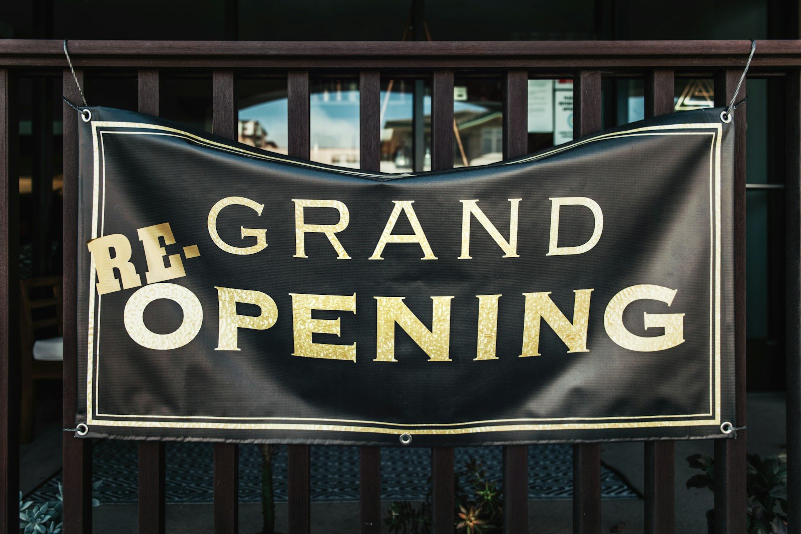 A printed vinyl grand opening banner mounted on a railing
